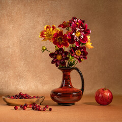 A bright bouquet of flowers in a clay jug. Fruits and berries on the table. Pomegranate and cranberry. Orange background. Healthy foods. Vegan. The taste and smell of autumn. Pleasant aroma. 
