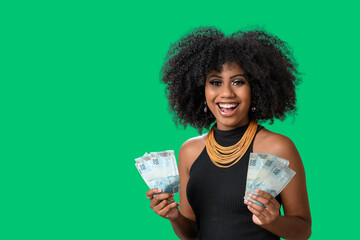 smiling woman holding money in her two hands, Brazilian money, isolated on green background