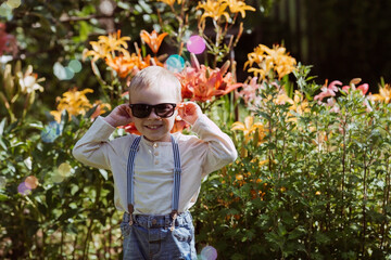 Cute happy boy playing with soap bubbles on a sunny summer day. A child in the fresh air, in...