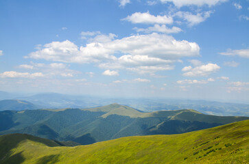 The landscape of the mountains. Beautiful mountain ranges with green hills and forest under blue sky on summer day. Carpathians, Ukraine
