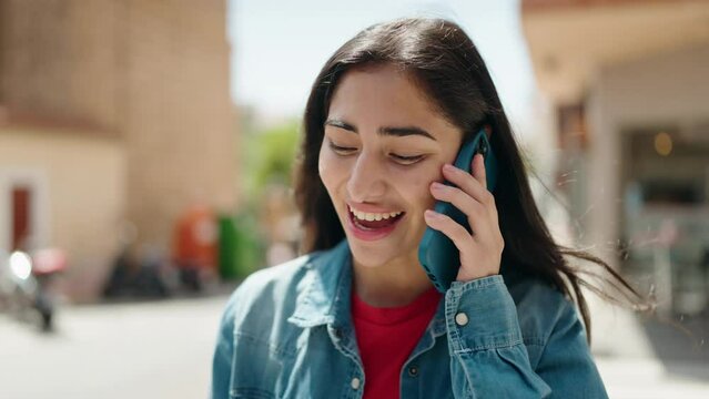 Young hispanic girl smiling confident talking on the smartphone at street