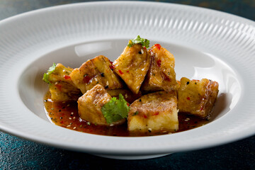 fried eggplant in sweet sour sauce on white plate macro close up