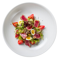 Salad Nicoise with fresh tuna and vegetables on a white plate top view isolated on white background