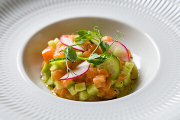 salmon Tartar with cucumber on a white plate macro close up