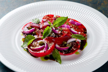 tomatoes bull's heart sliced with red onion on a white plate macro close up