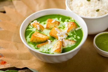 Palak Paneer with Naan served in Kadai with rice and mint sauce on old wooden table, indian cuisine