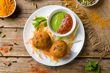 Indian samosa with vegetables, alu vonda with tomato mint sauce on old wooden table top view