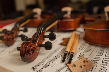 Violins on top of sheet music in a repair workshop © Guillermo Spelucin