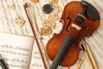 Naklejka premium Violin and bow with tools and music sheets in a workshop