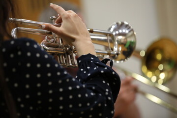 Hand of a woman holding and playing a musical instrument on a trumpet background image of the creative process close-up