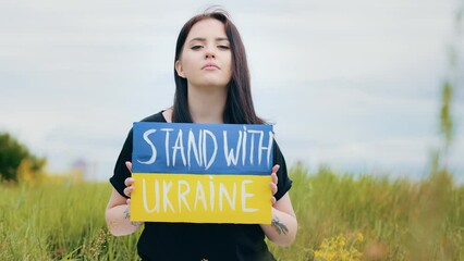 Depressive upset girl woman raises artwork banner cardboard with political inscription stand with Ukraine demonstrate protesting colorful yellow blue patriotic placard asks help for ukrainian nation