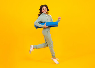 Run and jump. Teen girl 12, 13, 14 years old in sport suit. Fashion child in sportswear sportive clothing. Sportive fashionable outfit. Studio shot on yellow background.