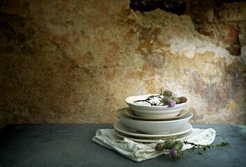 Set of vintage ceramics with dried thistle flowers against old brick wall with layers of old paint 