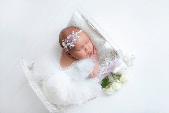 Beautiful little infant baby girl, has happy sleep face, dressed in suit and headband with flowers. Child close up portrait. Lifestyle instagram newborn concept. Amazing kids.