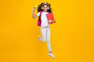 Fototapeta na wymiar Schoolgirl, teenage student girl in headphones hold books on yellow isolated studio background. School and music education concept. Back to school.