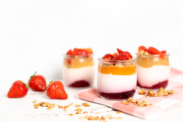 Fruit yogurt berry with muesli and fresh strawberries, on a white wooden background
