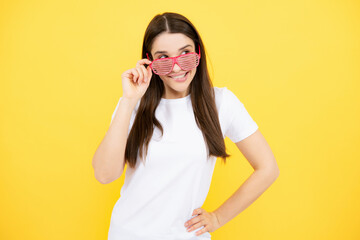 Beauty funny teenage girl with party glasses, yellow background. Surprised young woman with fun...