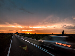 Fototapeta Droga krajowa i pędzący samochód o zachodzie słońca - Speeding car at sunset obraz