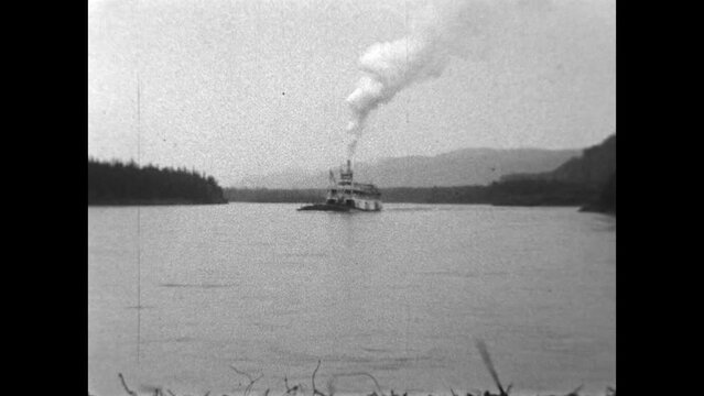 Passing Riverboat 1936 - The paddle wheel driven steamboat, Aksala, passes while pushing a barge on the Yukon River in 1936.