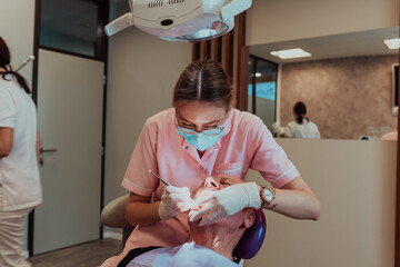 A dentist with the help of a colleague performs an operation on the jaw of an elderly patient in a...