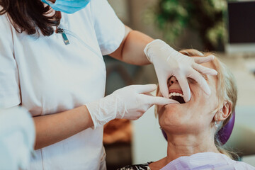Obraz na płótnie Canvas A dentist in a modern dental practice performs jaw surgery on an elderly patient