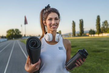 one woman adult caucasian female athlete standing on stadium on running track with supplement...