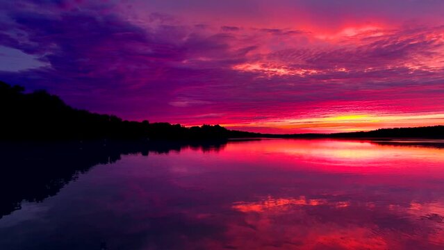 Amazing red sky mirrored in still waters at dawn, dynamic moving perspective.
