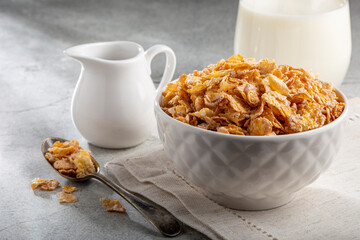 Corn flakes in bowl and glass of milk on table.
