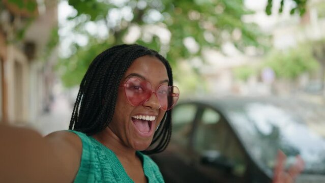 African american woman wearing heart sunglasses make selfie by smartphone at street