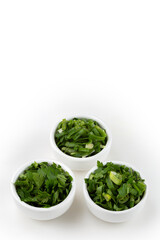 Sliced ​​cilantro, chives and parsley in ramekin.