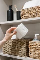Woman take toilet paper from storage shelf in bathroom