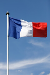 Fototapeta na wymiar French flag flying in the wind with blue sky background. Flag of France, the Tricolor on a White flagpole,