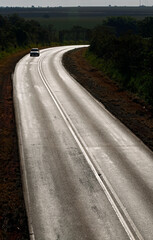 Naklejka premium Lone car on the highway illuminated by the sunset. Sao Paulo state, Brazil
