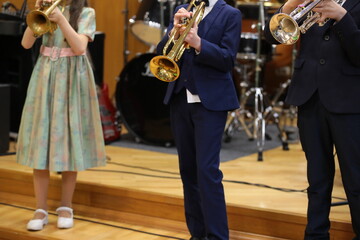 Young musicians girl and boys trumpeters playing the trumpet concert standing in a row on stage