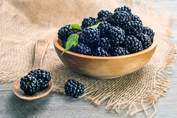 rblackberries in wooden bowl on a gray table.