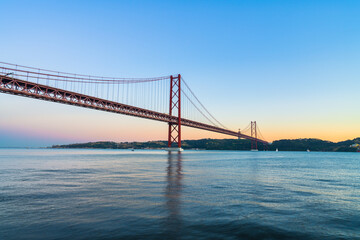 Fototapeta na wymiar The 25 de Abril bridge at sunset over the Tajo River in Lisbon. Portugal