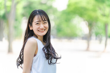 新緑の中にいる笑顔の日本人女性
