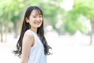 新緑の中にいる笑顔の日本人女性
