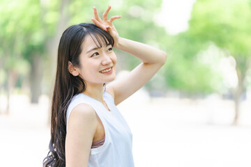 新緑の中で日光を浴びる日本人女性（紫外線対策・日焼け止め）

