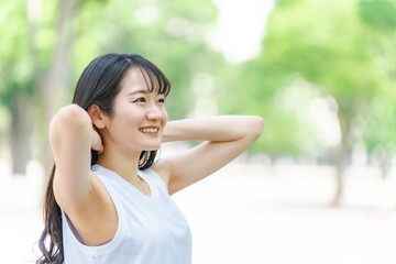 新緑の中で髪を触る笑顔の日本人女性（シャンプー・美髪）
