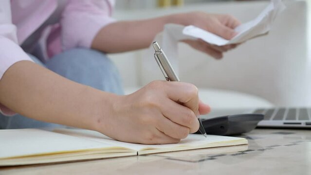 Closeup hands of woman calculating finance household with calculator on desk at home, girl checking bill for saving and planning expenses, debt and loan, tax and accounting, business and financial.