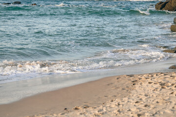 Gentle waves breaking on the beach with footprints in the soft sand