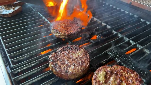 barbecue cutlets look very tasty cooked for a hamburger on a hot open fire on the grill turns over with a spatula after each turn the fire flares up and creates slow motion video for any restaurant.