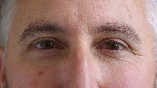 Closeup of eyes and mature man wearing eye contacts as an optometry vision or optician prescription solution. Headshot, face and skin or wrinkles detail of a man looking forward, watching and gazing