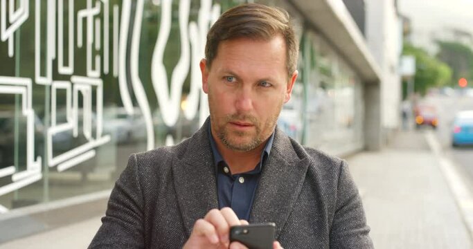 Paranoid mature man using a phone and worried about privacy and surveillance in a city. Concerned, worried man using technology app and vpn to block his location being tracked or followed outside
