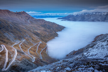 Stelvio pass, mountain road above misty clouds in Italian alps