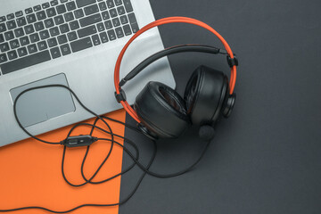 Large wired headphones on a laptop on a black and orange background. Creative workplace.