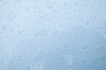 Clear water drops on transparent glass blue background 