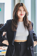 Portrait shot of millennial Asian cheerful successful professional businesswoman entrepreneur in formal suit standing smiling crossed arms in meeting room while employee and colleague brainstorming