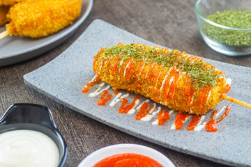 Mozarella Corndog served with mayonnaise, chili sauce and parsley. It has a savory taste and is cooked by frying